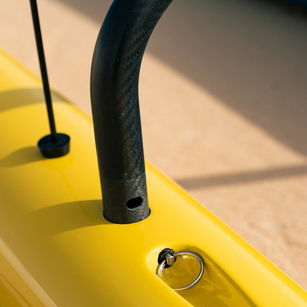 Close-up of the carbon fiber spar attachment on the yellow ama of a Nalu Blue Collection Synergy outrigger canoe.