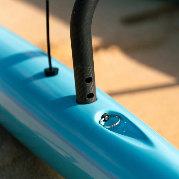A detail shot of the carbon fiber iako connecting to the teal ama of a Supernova outrigger canoe, secured with a stainless steel pin.