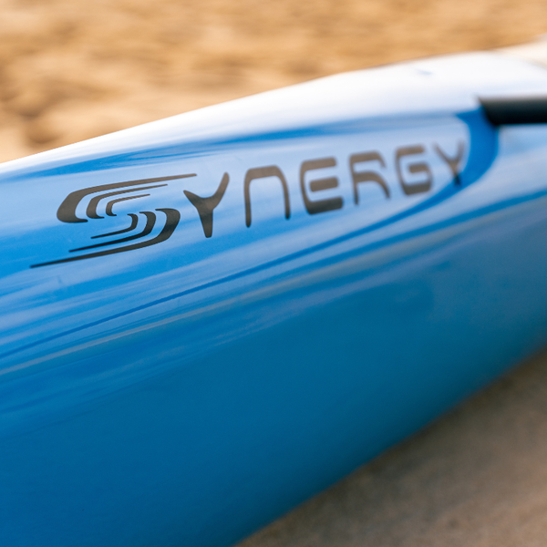 Close up of the black Synergy logo on a sleek blue Nalu high performance outrigger canoe hull.