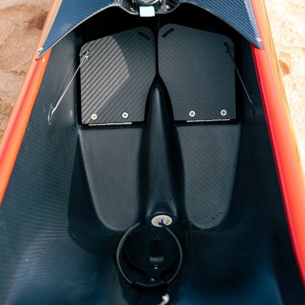 Interior close-up of a red Shaka high-performance canoe showing the precision carbon fiber foot wells and steering mechanisms for elite racing.