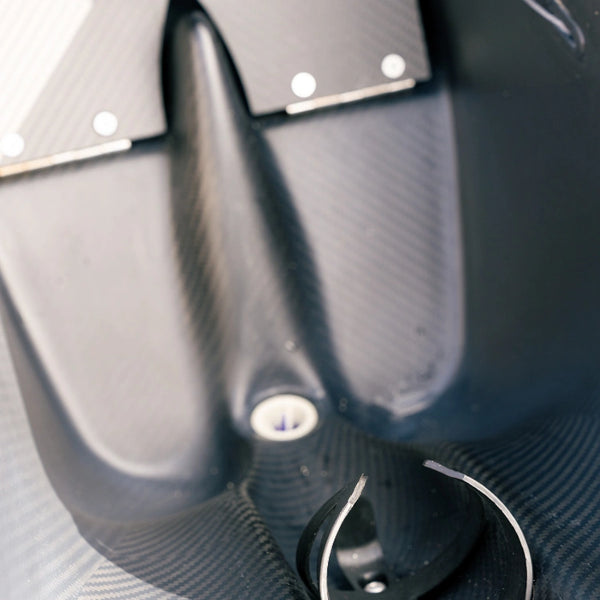 Detailed view of the internal steering cable assembly and carbon fiber construction inside a red Shaka high-performance racing canoe.