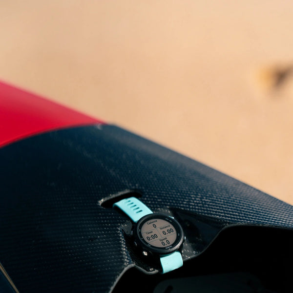 A performance Garmin GPS tracker mounted on the black carbon fiber deck of a red Shaka high-performance racing canoe.