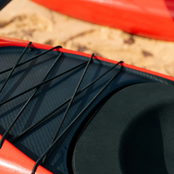 Close-up of the black bungee cord rigging and ergonomic seat design on a red high-performance racing canoe from the Nalu Shaka Collection.