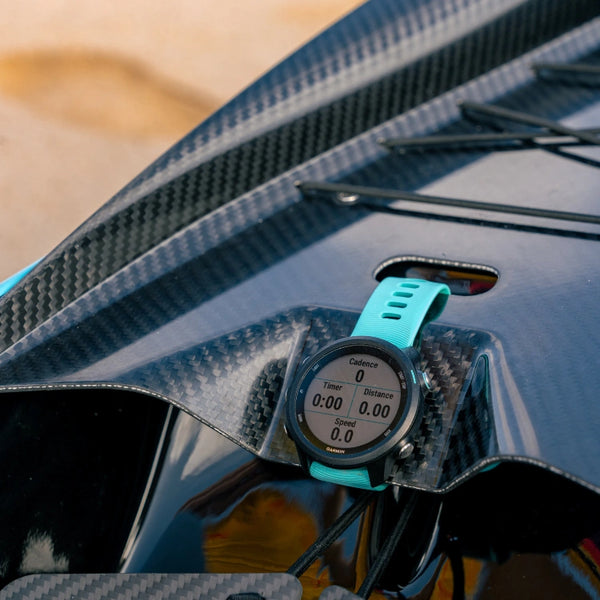 A close-up of a teal Garmin sports watch mounted on the carbon fiber deck of a canoe from the Supernova High Performance Collection, showing performance metrics.