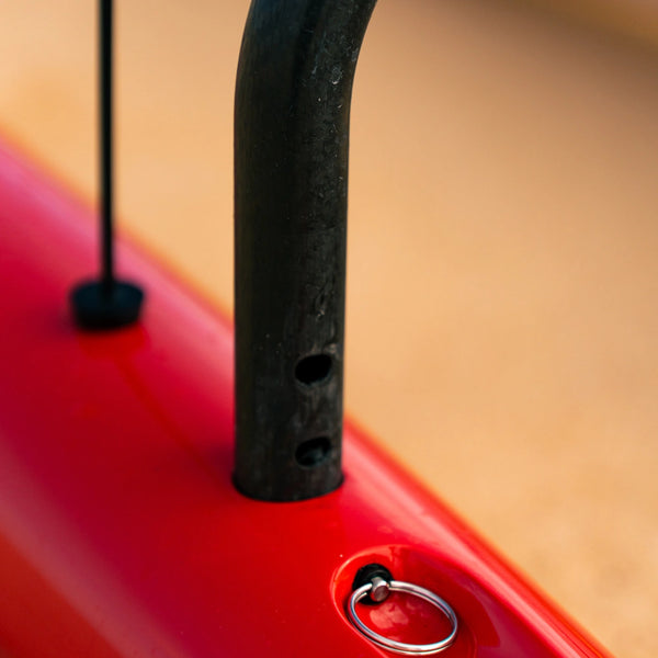 Macro shot of a black carbon fiber iako connected to a red outrigger ama with a stainless steel locking pin.