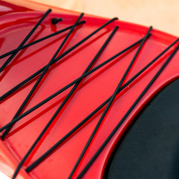 Detailed view of the black elastic cargo bungees crisscrossing the red deck of a Nalu performance outrigger canoe.